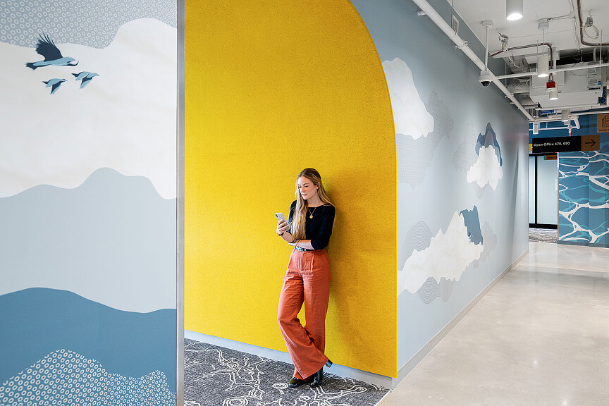 A person standing next to a wall with art on it.